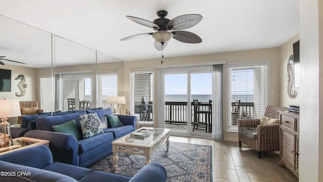 living room with ceiling fan and a water view