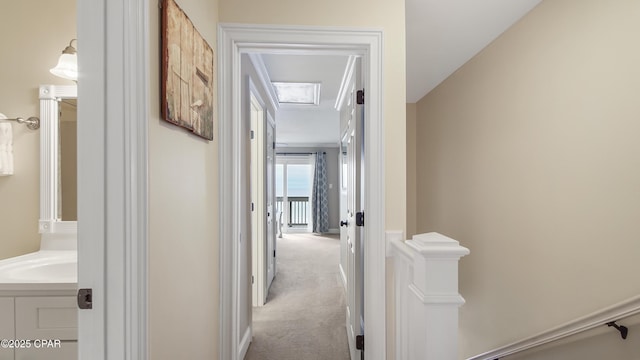 hallway featuring light carpet and sink