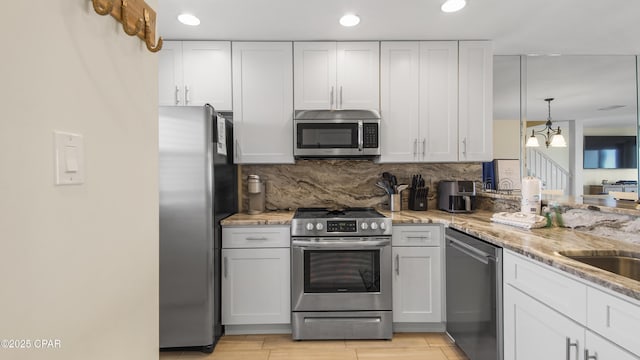 kitchen featuring appliances with stainless steel finishes, light stone counters, white cabinets, and backsplash