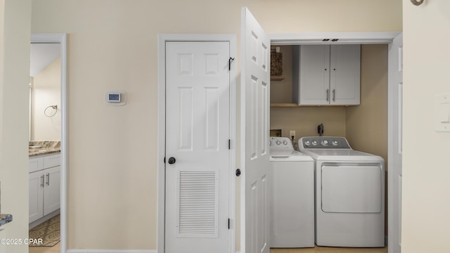 clothes washing area with cabinets and washing machine and clothes dryer