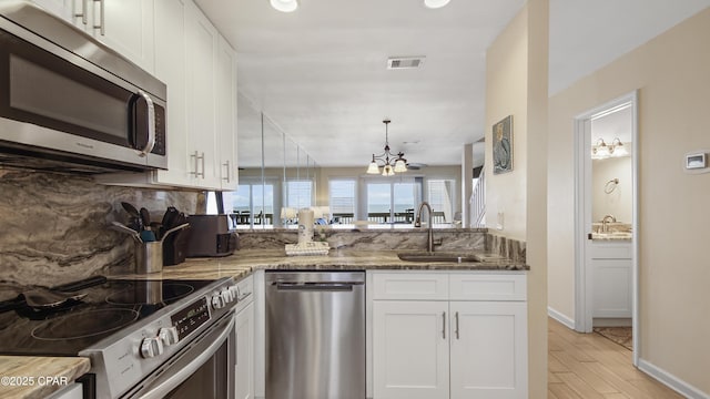 kitchen with sink, stainless steel appliances, light hardwood / wood-style floors, white cabinets, and dark stone counters