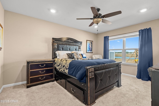 bedroom with a water view, ceiling fan, and light carpet