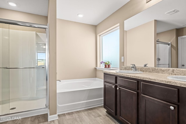 bathroom with a healthy amount of sunlight, vanity, plus walk in shower, and hardwood / wood-style floors