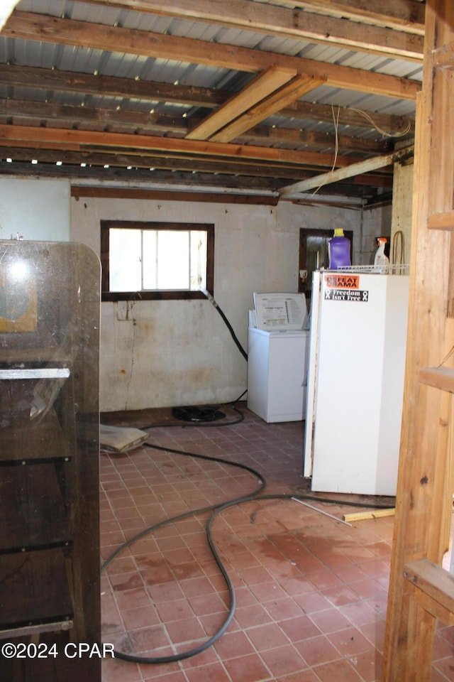 basement featuring fridge and washer / dryer