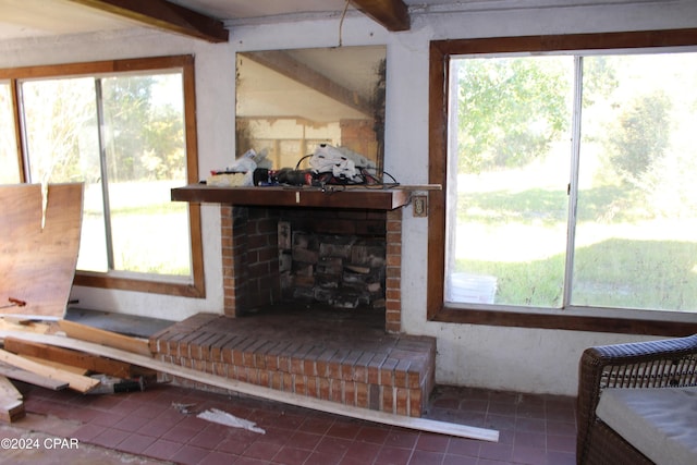 tiled living room with beamed ceiling, a brick fireplace, and a wealth of natural light