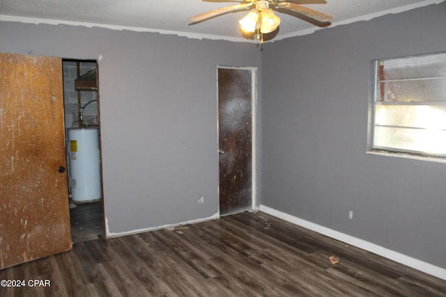 unfurnished room with ceiling fan, dark hardwood / wood-style flooring, and gas water heater