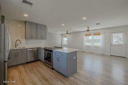 kitchen with kitchen peninsula, gray cabinets, ceiling fan, appliances with stainless steel finishes, and light hardwood / wood-style flooring