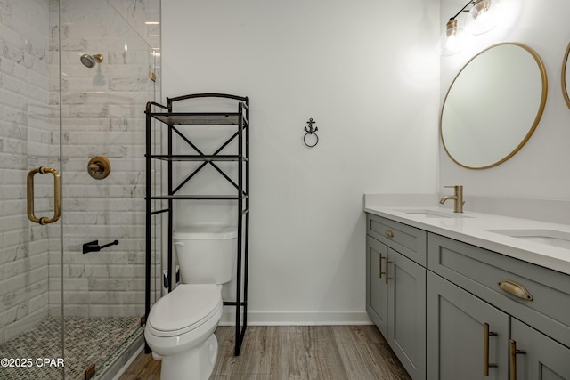 bathroom featuring toilet, vanity, a shower with door, and hardwood / wood-style flooring