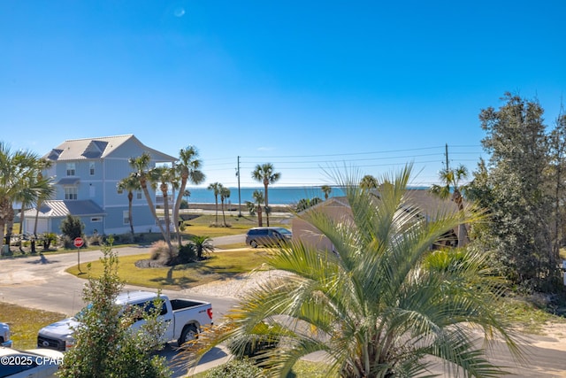 view of home's community with a water view and a lawn