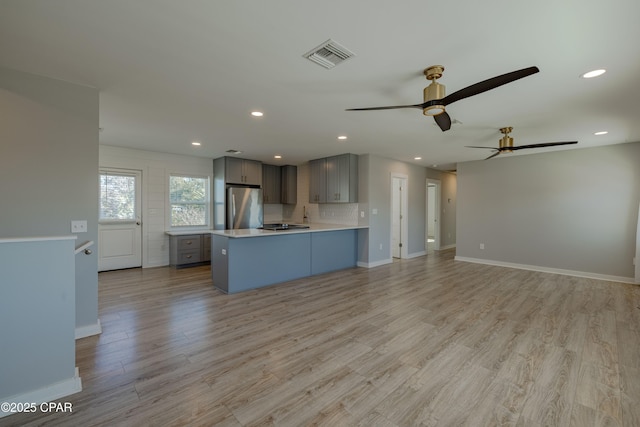 kitchen featuring ceiling fan, stainless steel fridge, gray cabinets, and light hardwood / wood-style flooring