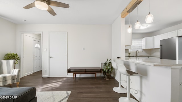 kitchen featuring dark hardwood / wood-style floors, white cabinets, a kitchen bar, decorative light fixtures, and kitchen peninsula