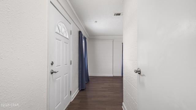 hall with crown molding, dark wood-type flooring, and a textured ceiling