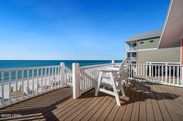 wooden deck featuring a water view and a beach view