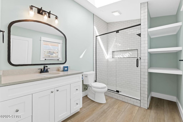 bathroom featuring vanity, a skylight, toilet, walk in shower, and hardwood / wood-style flooring