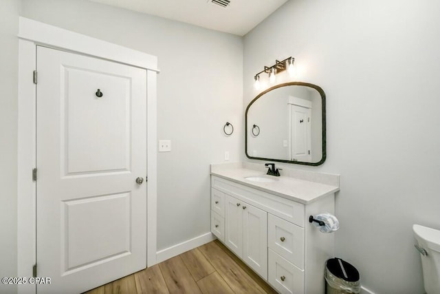 bathroom with hardwood / wood-style flooring, toilet, and vanity