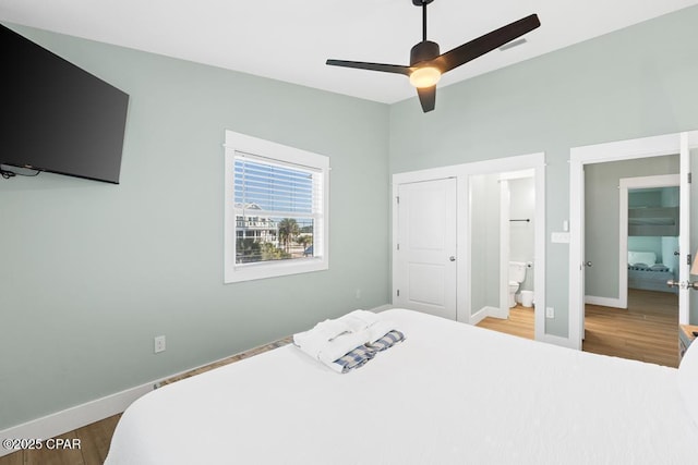 bedroom featuring ceiling fan, ensuite bath, and wood-type flooring