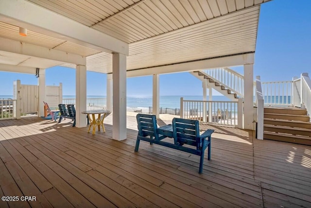 deck featuring an outdoor hangout area, a water view, and a view of the beach