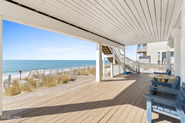 wooden terrace with a water view and a view of the beach