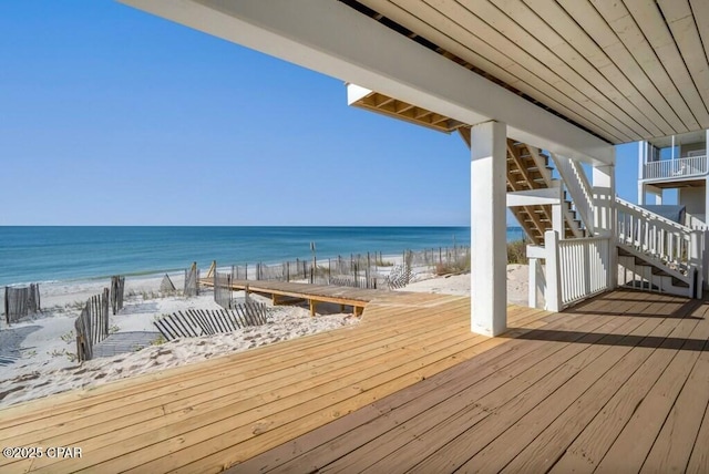 wooden deck featuring a view of the beach and a water view