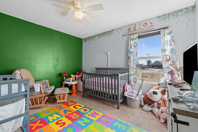 bedroom with a nursery area, carpet floors, a textured ceiling, and ceiling fan