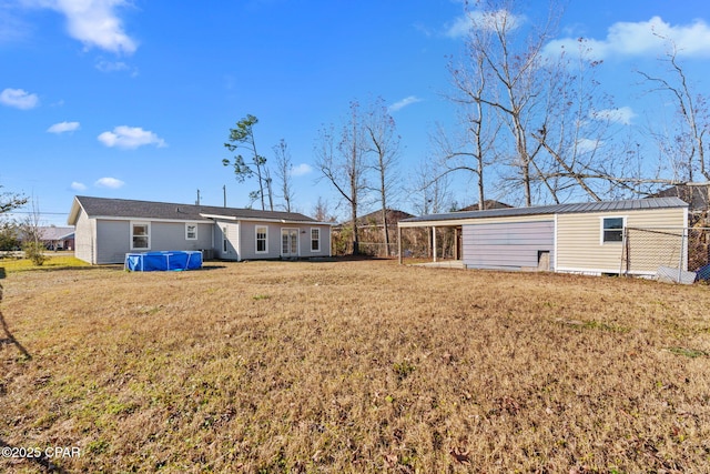 rear view of house with a swimming pool and a lawn