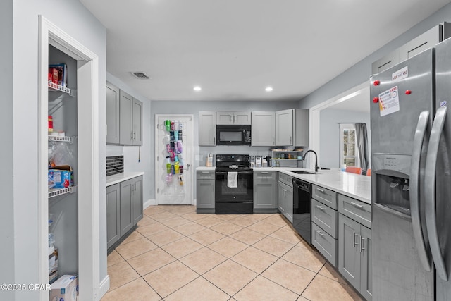 kitchen with gray cabinetry, light tile patterned floors, sink, and black appliances