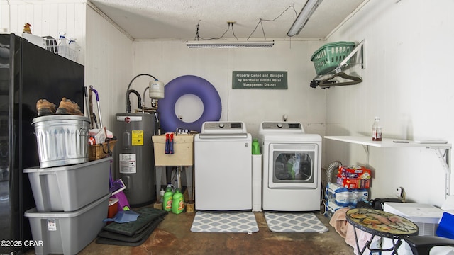 washroom featuring a textured ceiling, washer and clothes dryer, electric water heater, and sink