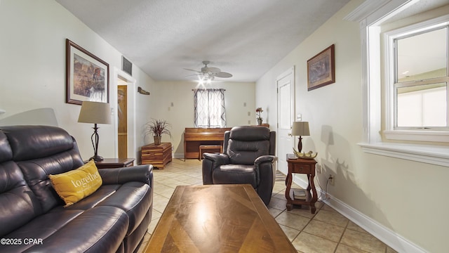 living room featuring a textured ceiling, ceiling fan, and light tile patterned floors