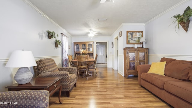 living room featuring ceiling fan, crown molding, a textured ceiling, and light hardwood / wood-style floors