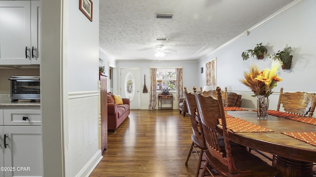 dining area featuring ceiling fan, a textured ceiling, dark hardwood / wood-style flooring, and crown molding