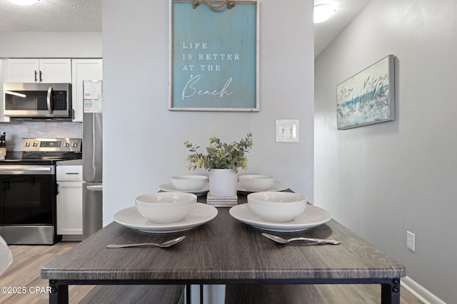 dining space with a textured ceiling and light hardwood / wood-style floors