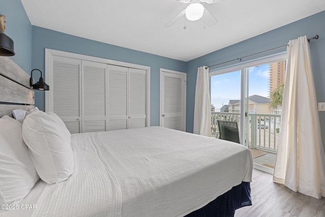 bedroom featuring ceiling fan, access to exterior, light hardwood / wood-style floors, and two closets