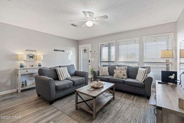 living room with a textured ceiling, ceiling fan, and hardwood / wood-style flooring