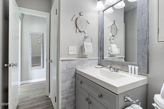 17670 Front Beach Rd Unit I7, Panama City Beach, FL 32413 - bathroom featuring tile walls, wood finished floors, toilet, vanity, and wainscoting