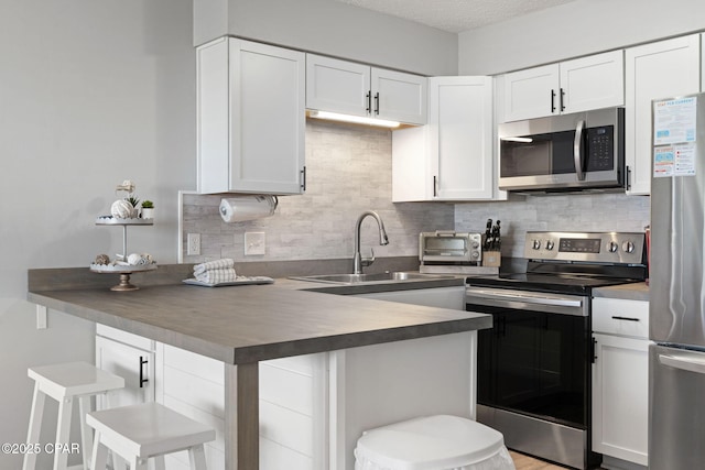 kitchen with backsplash, appliances with stainless steel finishes, a kitchen breakfast bar, and white cabinets