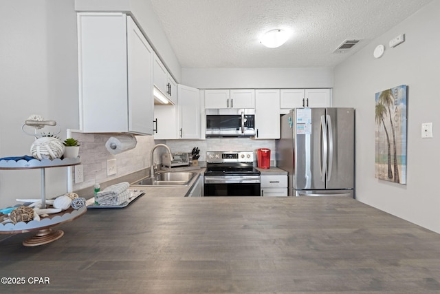 kitchen featuring sink, tasteful backsplash, a textured ceiling, appliances with stainless steel finishes, and white cabinets