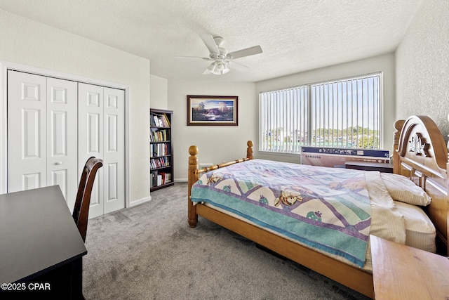 carpeted bedroom with ceiling fan, a textured wall, a closet, and a textured ceiling