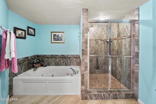 full bath with a tub with jets, a shower stall, and a textured ceiling