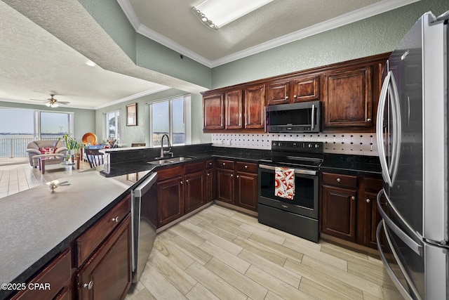 kitchen featuring a sink, a textured ceiling, appliances with stainless steel finishes, crown molding, and a textured wall