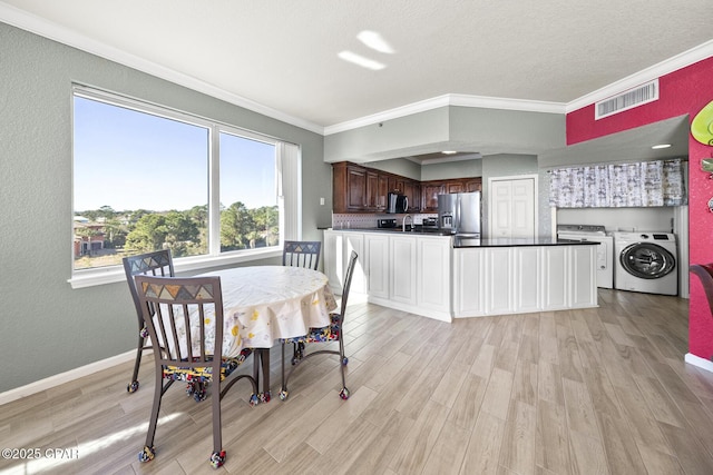 dining space with light wood-style floors, separate washer and dryer, visible vents, and ornamental molding