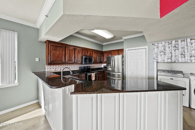 kitchen with light wood-style flooring, ornamental molding, appliances with stainless steel finishes, washer and dryer, and a textured wall