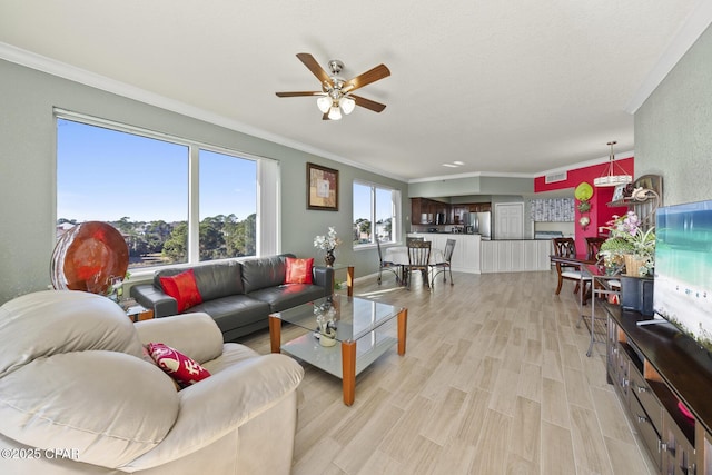 living area featuring ceiling fan, light wood-style flooring, baseboards, and ornamental molding