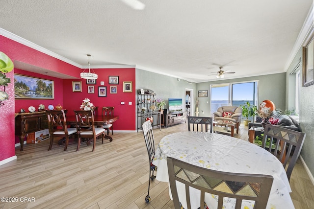 dining space with a ceiling fan, baseboards, light wood-style flooring, ornamental molding, and a textured ceiling