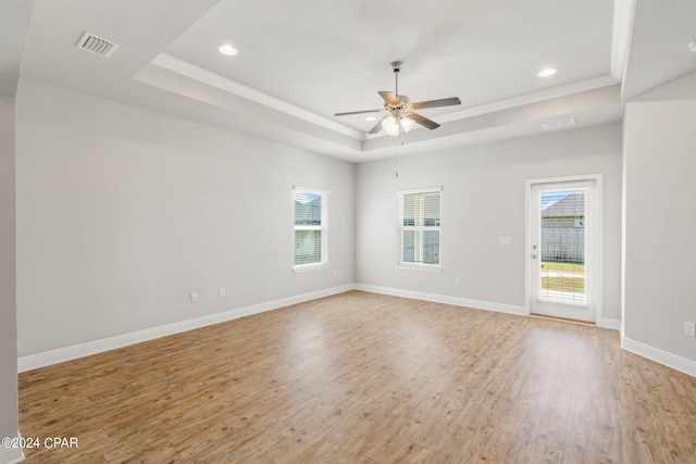 spare room featuring ornamental molding, plenty of natural light, a raised ceiling, and light hardwood / wood-style flooring