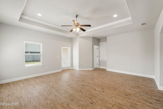 spare room with ceiling fan, a tray ceiling, and light hardwood / wood-style floors