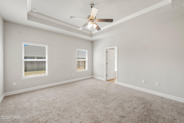 unfurnished room with ornamental molding, light colored carpet, ceiling fan, and a tray ceiling