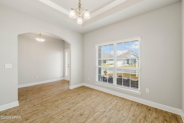 unfurnished room with hardwood / wood-style flooring, a raised ceiling, and a chandelier