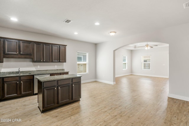 kitchen with sink, dark brown cabinets, stainless steel dishwasher, and light wood-type flooring