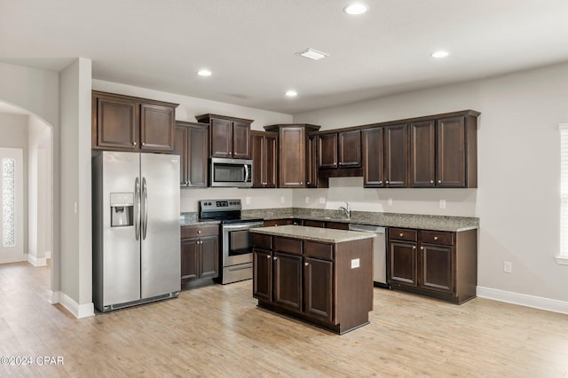 kitchen featuring stainless steel appliances, light wood-type flooring, and dark brown cabinetry