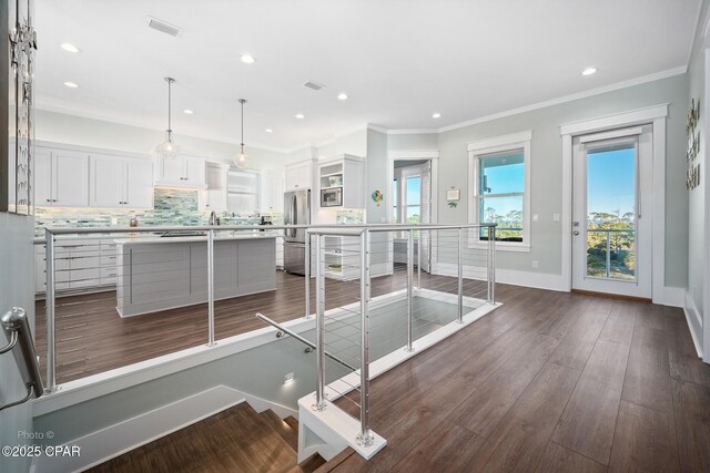 interior space featuring white cabinets, a kitchen island, dark wood-type flooring, hanging light fixtures, and stainless steel refrigerator